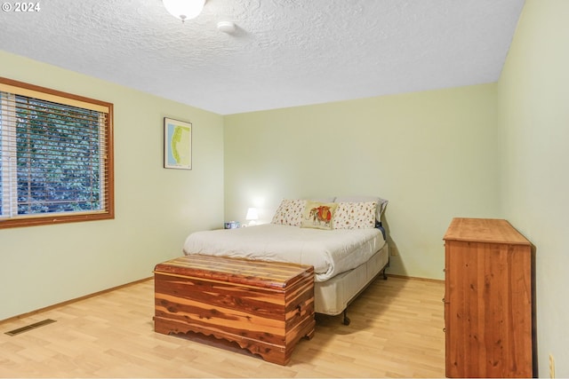 bedroom featuring light wood-type flooring and a textured ceiling