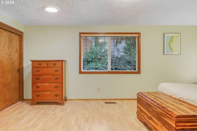 bedroom with a textured ceiling and light hardwood / wood-style floors