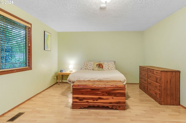 bedroom featuring a textured ceiling and light hardwood / wood-style flooring