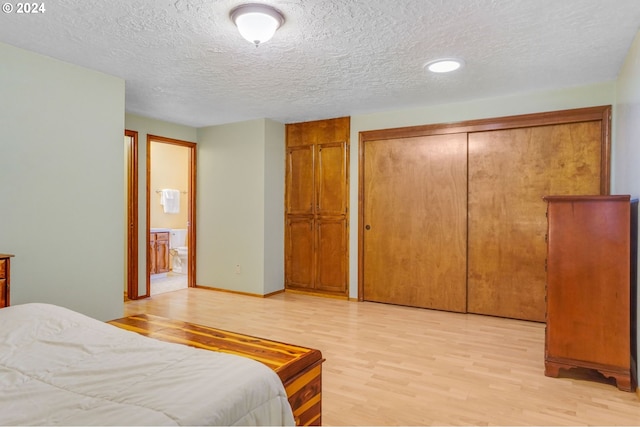 bedroom featuring a textured ceiling, light wood-type flooring, and a closet