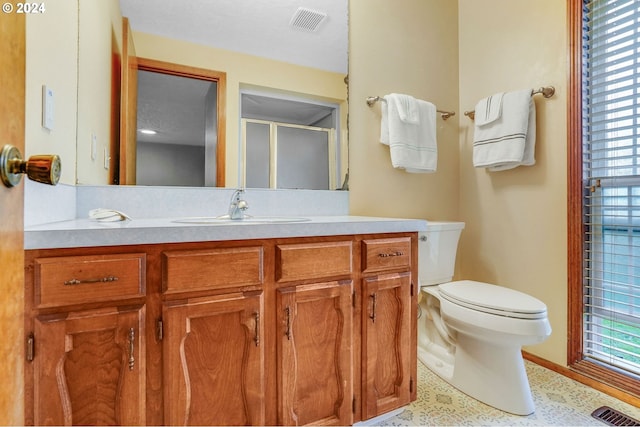 bathroom with vanity, a shower with shower door, and toilet