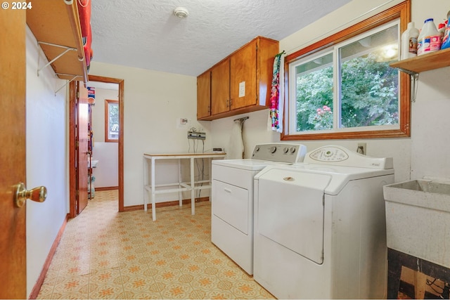 laundry area with cabinets, a textured ceiling, independent washer and dryer, and sink