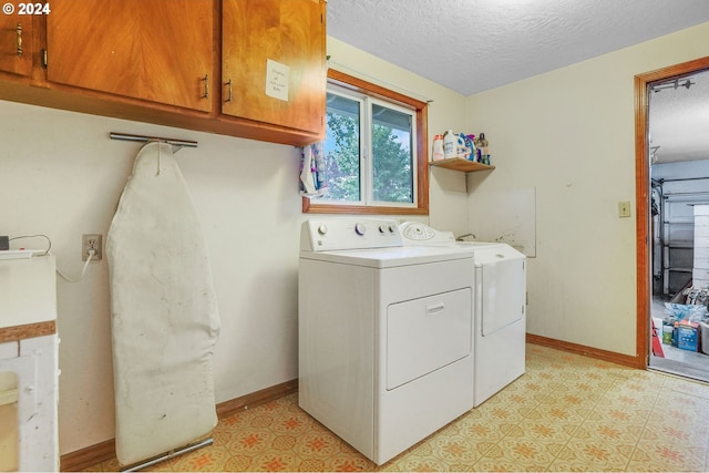 washroom featuring cabinets, a textured ceiling, and washing machine and clothes dryer