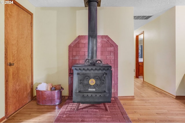 details featuring a wood stove, a textured ceiling, and hardwood / wood-style floors