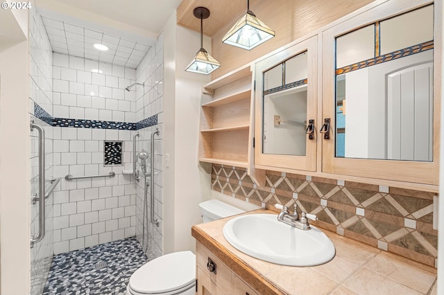 bathroom with vanity, a tile shower, toilet, and tasteful backsplash