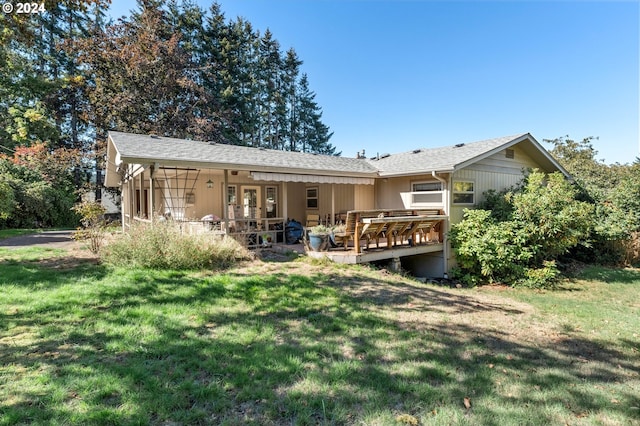 rear view of property with a wooden deck and a lawn