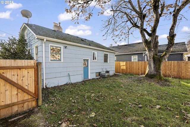 back of house featuring central AC unit and a yard