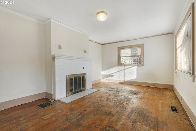 unfurnished living room with light hardwood / wood-style floors, a brick fireplace, and ornamental molding