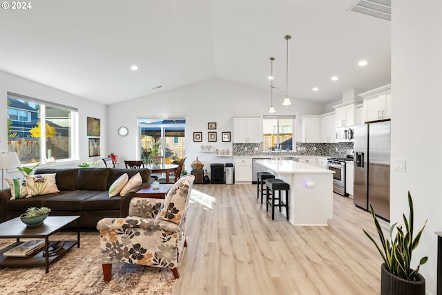 living room with sink, vaulted ceiling, and light hardwood / wood-style floors