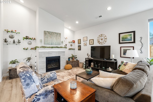 living room featuring wood-type flooring, a tile fireplace, and vaulted ceiling