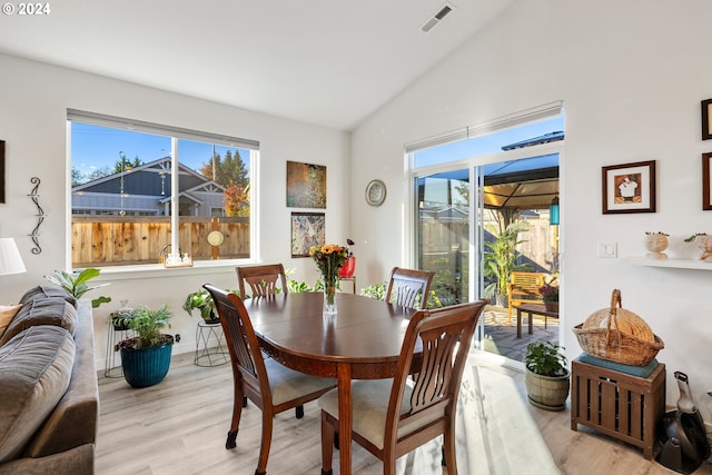 dining room with high vaulted ceiling and light hardwood / wood-style flooring