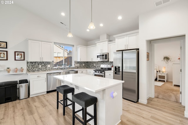 kitchen with white cabinets, stainless steel appliances, hanging light fixtures, and a center island