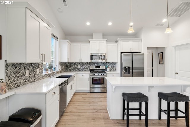 kitchen featuring pendant lighting, white cabinets, a center island, and stainless steel appliances