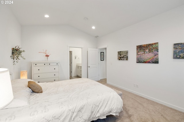 bedroom with lofted ceiling, light colored carpet, and ensuite bath