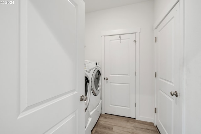 laundry area with light hardwood / wood-style flooring and washer and clothes dryer