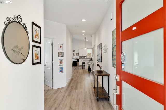 hall with light hardwood / wood-style floors and vaulted ceiling