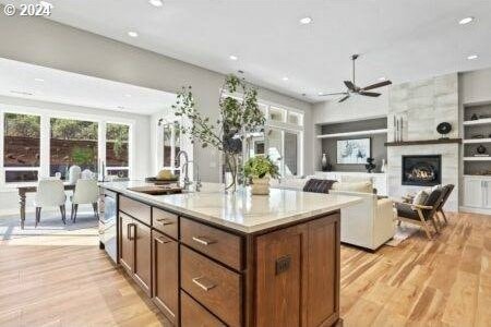 kitchen featuring a fireplace, light hardwood / wood-style floors, a center island, ceiling fan, and sink