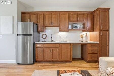 kitchen with stainless steel fridge, sink, and light hardwood / wood-style floors