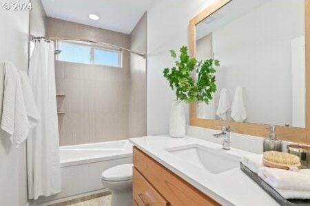 full bathroom featuring shower / tub combo with curtain, vanity, and toilet