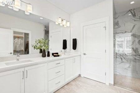 bathroom with a tile shower, double sink vanity, and tile patterned flooring