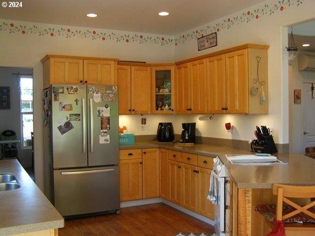 kitchen with a breakfast bar, stainless steel refrigerator, dark hardwood / wood-style floors, kitchen peninsula, and a wall mounted AC