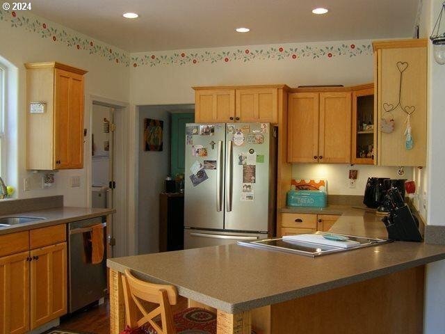 kitchen featuring appliances with stainless steel finishes, sink, kitchen peninsula, and a kitchen bar