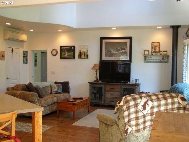 living room with a wall unit AC and dark hardwood / wood-style flooring