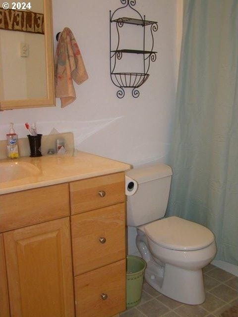 bathroom featuring toilet, tile flooring, and vanity