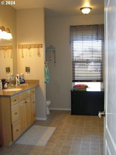 bathroom with large vanity, tile floors, and toilet