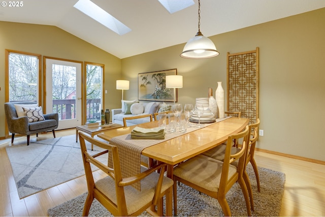 dining space featuring lofted ceiling with skylight and light wood-type flooring