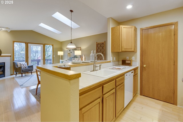 kitchen featuring dishwasher, kitchen peninsula, a tile fireplace, and sink