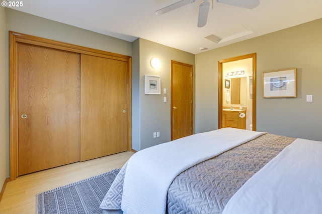 bedroom featuring ceiling fan, light hardwood / wood-style floors, a closet, and ensuite bath