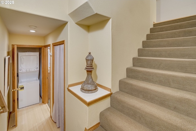 stairway with hardwood / wood-style floors and stacked washer / drying machine