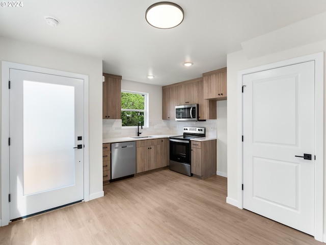 kitchen with decorative backsplash, stainless steel appliances, light wood-type flooring, and sink