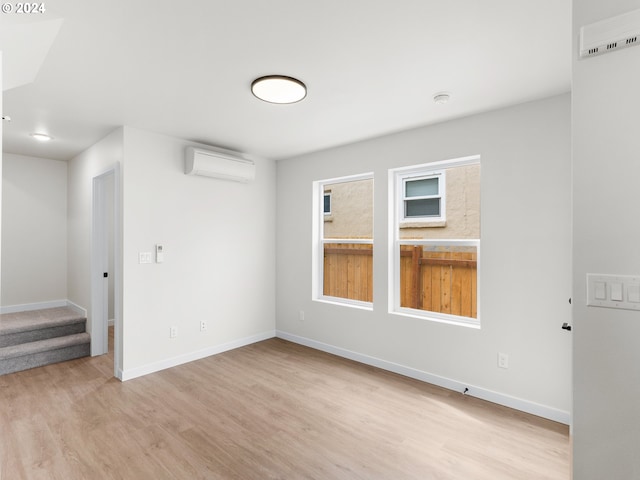 unfurnished room featuring light hardwood / wood-style flooring and a wall mounted air conditioner