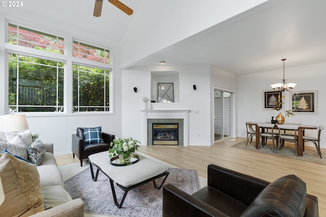 living room featuring lofted ceiling, wood-type flooring, and ceiling fan with notable chandelier