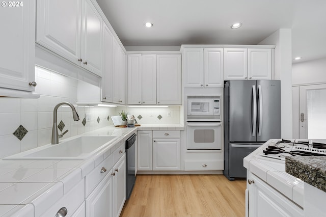 kitchen featuring white cabinets, appliances with stainless steel finishes, light hardwood / wood-style flooring, and sink