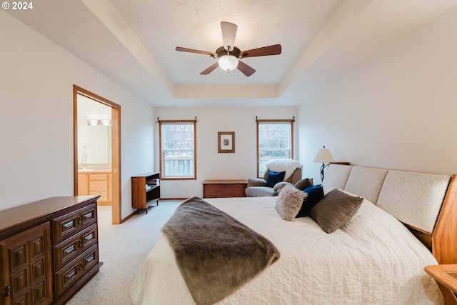 carpeted bedroom featuring ceiling fan, a raised ceiling, sink, and connected bathroom