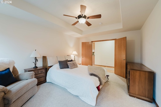 carpeted bedroom featuring a raised ceiling and ceiling fan