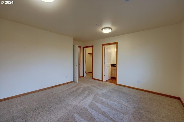 unfurnished bedroom with connected bathroom and light carpet