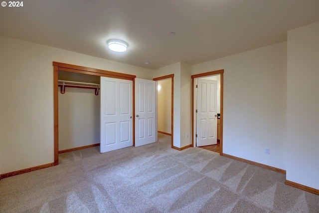 unfurnished bedroom with light colored carpet and a closet