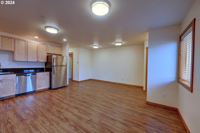 kitchen with stainless steel appliances, light brown cabinetry, sink, and light hardwood / wood-style flooring