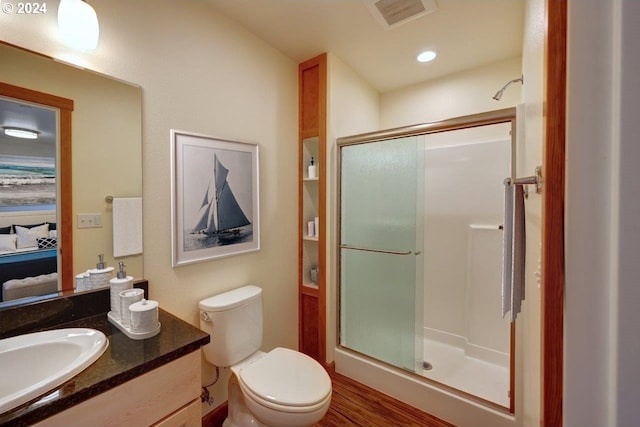 bathroom with hardwood / wood-style floors, vanity, toilet, and an enclosed shower