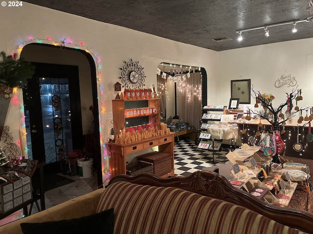 living room with tile patterned floors, visible vents, track lighting, and arched walkways