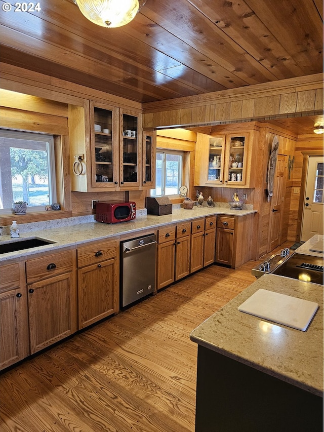 kitchen with light stone countertops, wood ceiling, wooden walls, sink, and light wood-type flooring