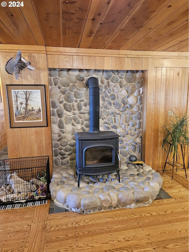 interior details with a wood stove, wooden ceiling, wooden walls, and wood finished floors