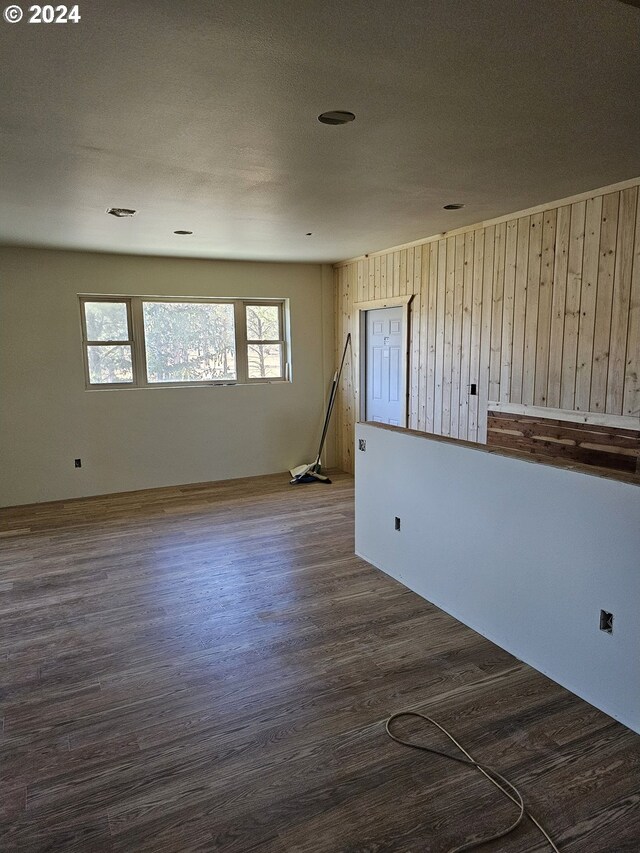 empty room with dark hardwood / wood-style floors and wooden walls