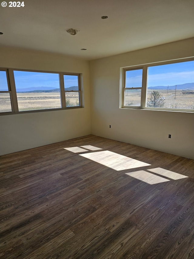 spare room with a mountain view and dark hardwood / wood-style flooring