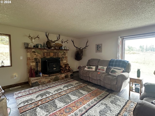 living room featuring a wood stove, plenty of natural light, a textured ceiling, and hardwood / wood-style flooring