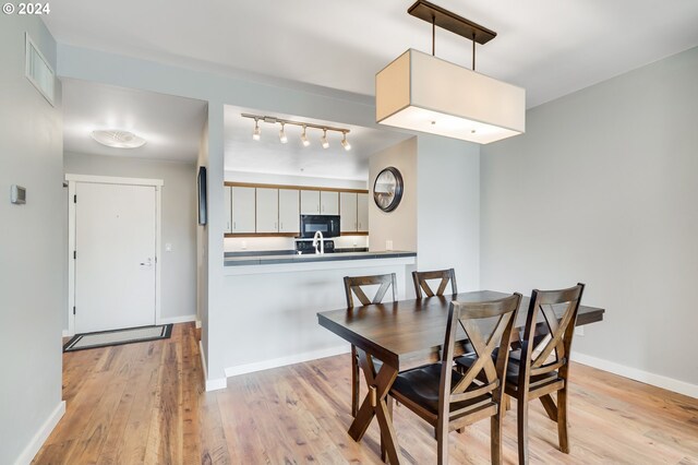 dining space with light wood-type flooring and track lighting